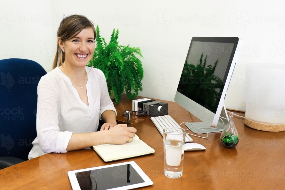 portrait of young professional woman looking at camera from her office desk austockphoto 000037342
